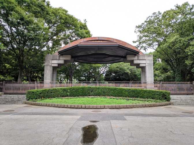 A small outdoor concert area. Benches are behind the fence.